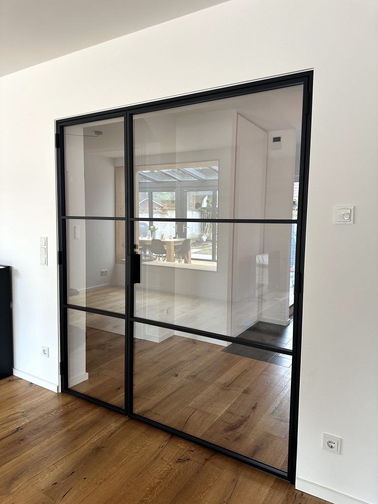 Moderne einflügelige Lofttür aus schwarzem Stahl mit Klarglas als Raumtrenner im Wohnbereich – maßgefertigte Lofttüren für stilvolle Wohnräume in Trier, Konz und Luxemburg