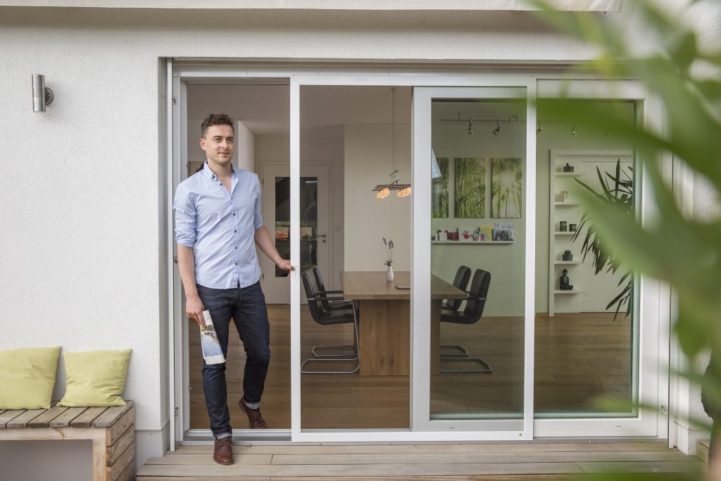 Moderner Wohn- und Essbereich mit bodentiefen Schiebetüren zur Terrasse, offene Raumgestaltung mit Esstisch und Designstühlen, fließender Übergang zwischen Innen- und Außenbereich für zeitgemäßes Wohnen
