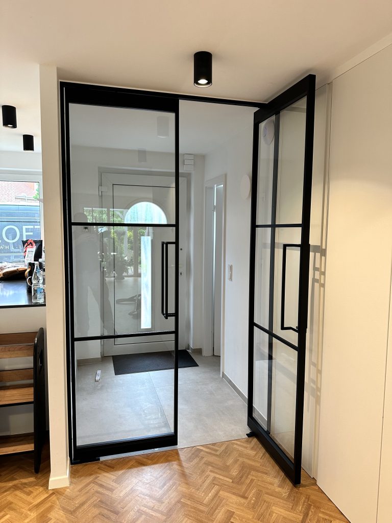 Doppelflügelige Pivot-Lofttür aus schwarzem Stahl mit Klarglas im modernen Eingangsbereich – maßgefertigte Lofttüren und Glastrennwände für Wohn- und Geschäftsräume in Trier, Konz und Luxemburg
