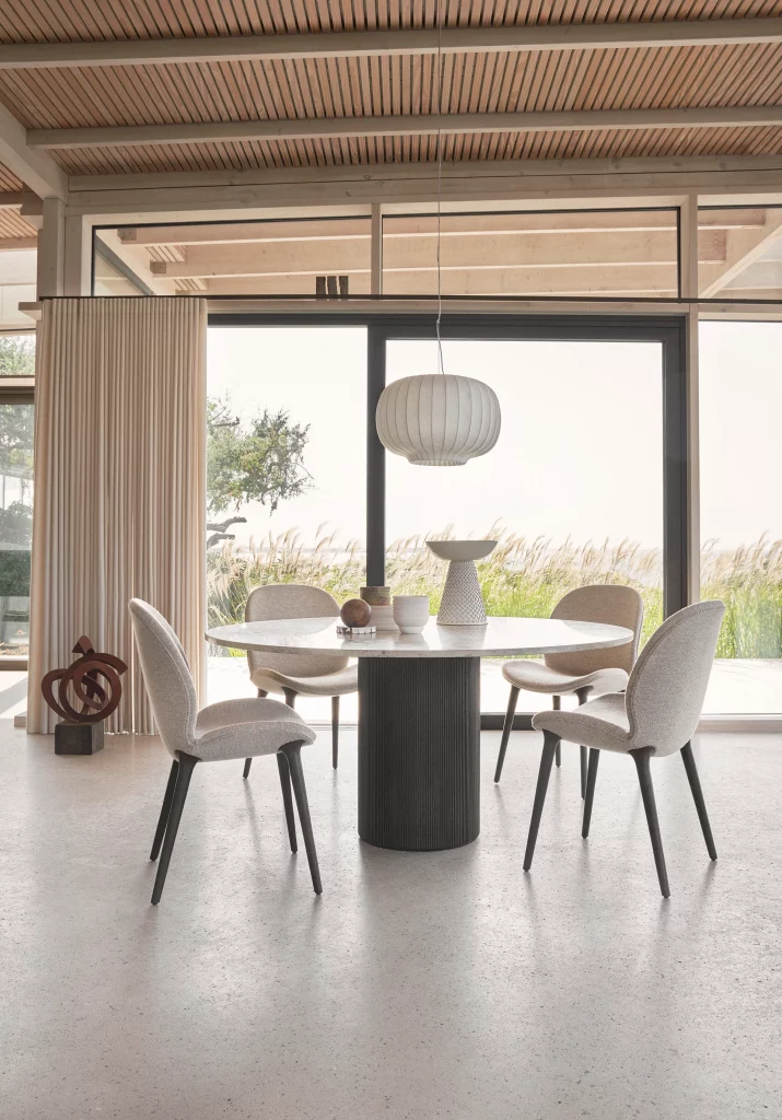 Runder Designer-Esstisch mit gepolsterten Stühlen vor Panoramafenster – hochwertige Esszimmer- und Designmöbel für moderne Wohn- und Geschäftsräume in Trier, Konz und Luxemburg